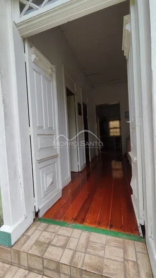 Corredor com piso de madeira e portas brancas.