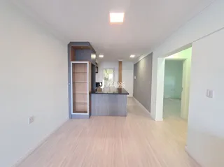 Interior de um ambiente com piso de madeira clara e paredes brancas.