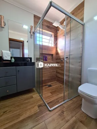 Foto de um banheiro com revestimento de madeira e box de vidro.
