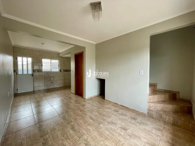 Hall de entrada com piso de cerâmica e escadaria visível.