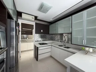 Cozinha moderna com armários escuros, bancadas brancas e revestimento de metal.