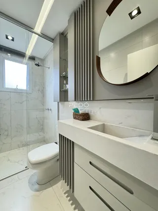 Banheiro moderno com box de vidro e revestimento em mármore claro.