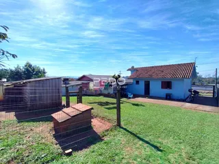 Vista externa de uma casa com quintal e cerca de madeira no primeiro plano.