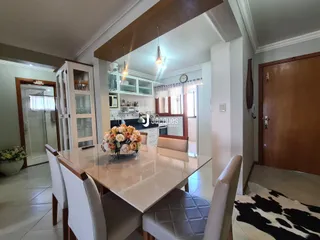 Uma sala de jantar com mesa de vidro e armários na cozinha.