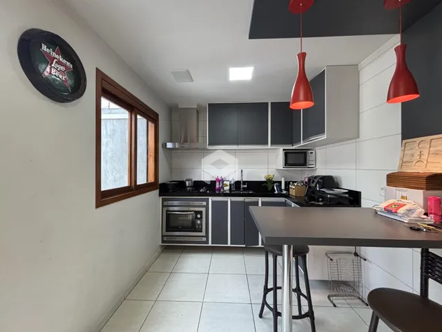 Cozinha moderna com armários escuros e iluminação pendente sobre a bancada.