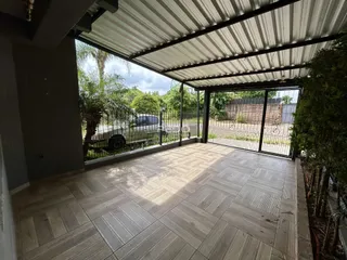 Área externa coberta com piso de cerâmica e estrutura de metal.
