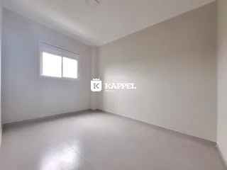 Sala de estar ampla com paredes brancas e piso claro.