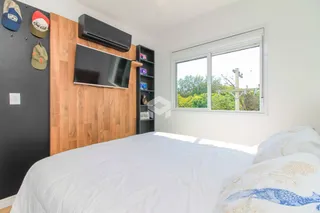 Quarto com cama e janela em ambiente claro.