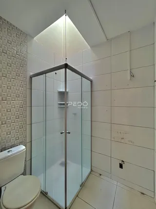 Banheiro com box de vidro e revestimento de azulejos brancos.