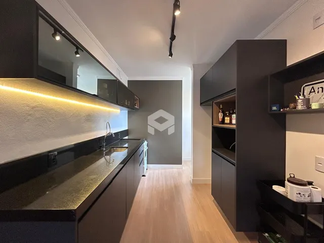 Interior da cozinha moderna com armários escuros e piso de madeira clara.