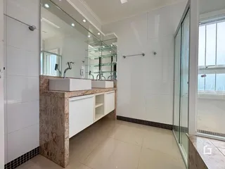 Banheiro moderno com revestimento branco e bancada de pedra.