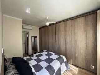 Quarto com armários em madeira e cama.