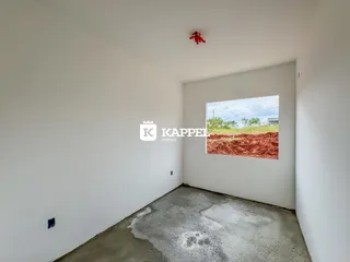 Foto de um cômodo vazio com piso de concreto e uma vista para um campo seco.