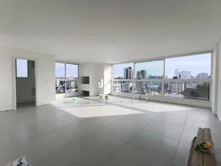 Ambiente interno de um imóvel com grandes janelas que oferecem vista para a cidade.