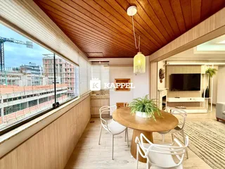 Sala de jantar com mesa de madeira e vista da cidade através de uma grande janela.