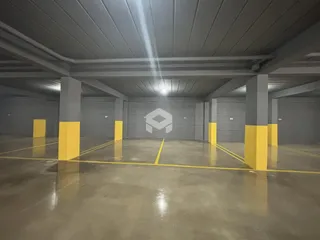 Imagem de um espaço interno com piso de concreto e vigas expostas.