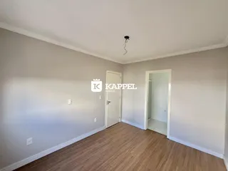 Interior de uma sala com paredes claras e piso de madeira.
