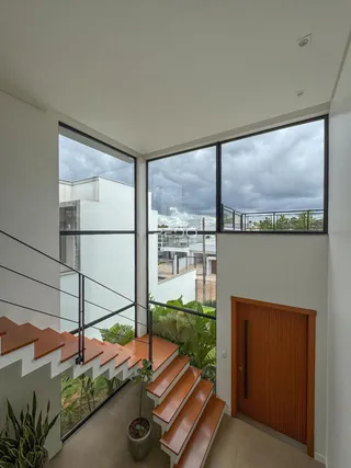 Vista de um corredor com escadaria e grandes janelas de vidro.