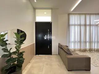 Sala de estar com porta escura e janela com cortinas claras.