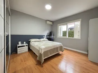 Quarto com cama e janela em ambiente com paredes cinzas.