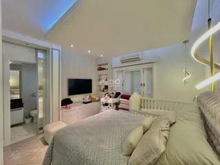 Quarto com cama e televisão em ambiente claro.