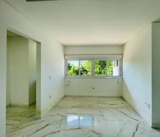 Interior de uma sala com piso de mármore claro e janela.