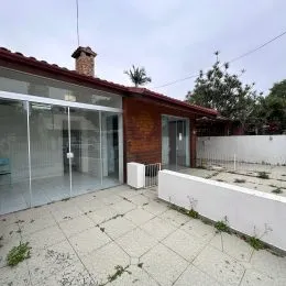 Vista externa de um pátio com piso de concreto adjacente a uma estrutura de vidro.