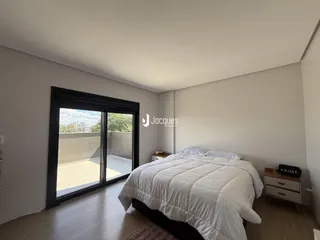O quarto possui piso de madeira e uma porta de vidro que dá acesso a uma área externa.