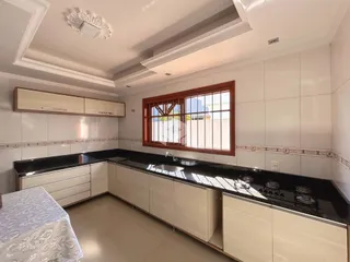 Uma cozinha com armários brancos e bancadas escuras.