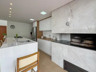 Cozinha moderna com armários brancos e bancada de mármore clara.