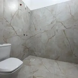 Foto interna de um banheiro com paredes revestidas em mármore claro.