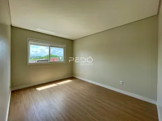 Sala de estar com piso de madeira clara e vista para o exterior.