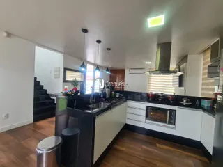 Cozinha moderna com armários brancos e bancadas escuras.