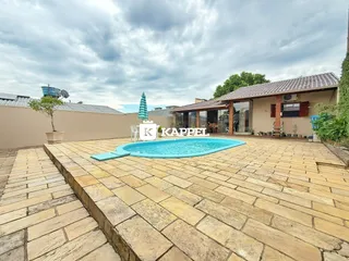 Foto da área externa com piscina e deck de pedra.