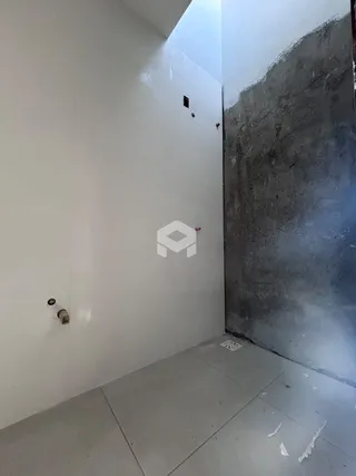 Vista de um corredor interno com paredes brancas e uma parede de concreto aparente.