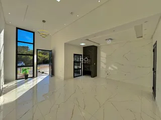 Sala de estar ampla com piso de mármore claro e grandes janelas.