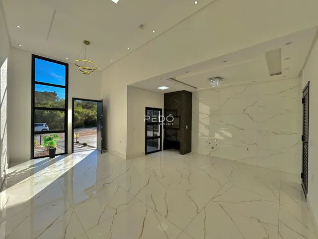 Sala de estar ampla com piso de mármore claro e grandes janelas.