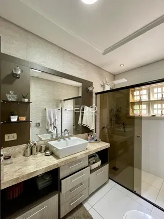 Foto de um banheiro com bancada e box de vidro.