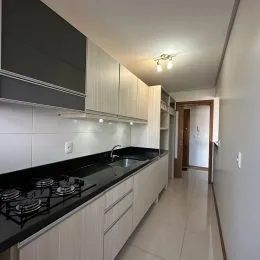 Foto de uma cozinha com armários brancos e bancadas escuras.