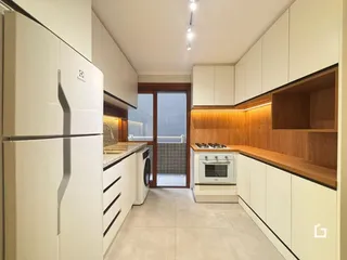 Cozinha moderna com armários brancos e detalhes em madeira.