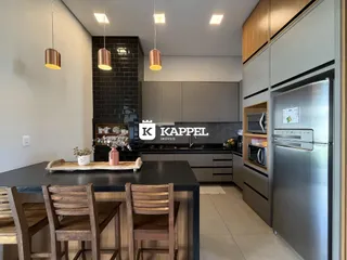 Cozinha moderna com bancada escura e armários em tons neutros.