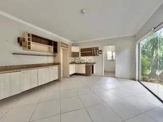 Ambiente interno de uma cozinha aberta com piso de cerâmica e armários brancos.