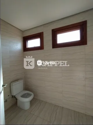 Foto de um banheiro com revestimento de azulejo claro e janela.