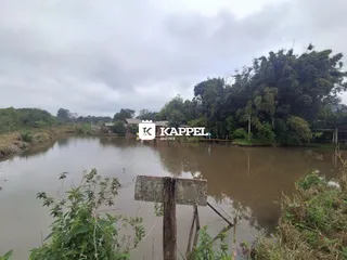 Vista panorâmica de um rio com vegetação densa e uma estrutura ao fundo.