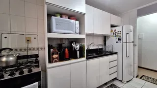 Foto de uma cozinha com armários brancos e eletrodomésticos.