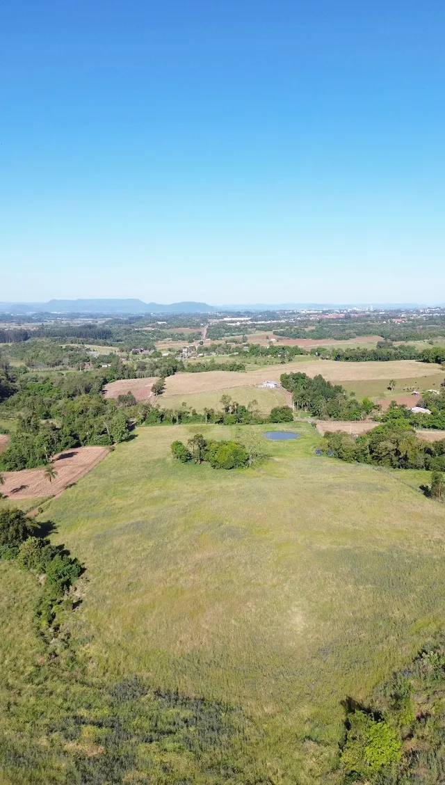 Vista aérea de campos verdes e vegetação em uma paisagem rural.