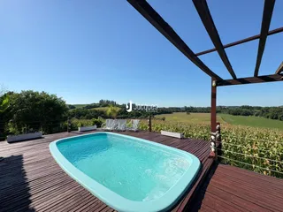 Uma piscina com deck de madeira em uma vista de campo.