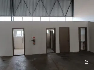 Vista interna de um ambiente com paredes brancas e portas de acesso.