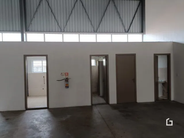 Vista interna de um ambiente com paredes brancas e portas de acesso.