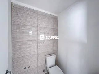 Foto de um banheiro com revestimento de azulejos e um vaso sanitário branco.